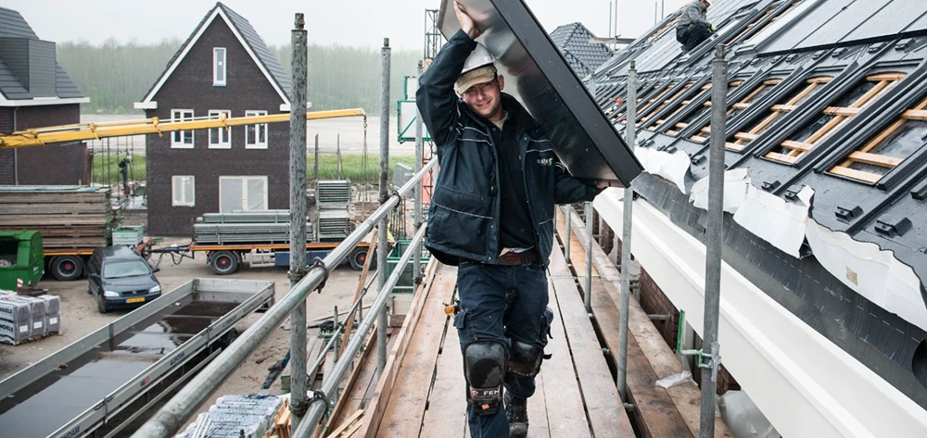 Installateur die zonnecollector op het dak tilt in Almere