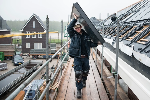 Installateur die zonnecollector op het dak tilt in Almere