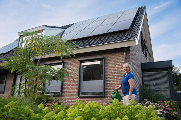 Vrouw in haar tuin met PVT panelen op het dak, onderdeel van het PVT systeem van HR energy