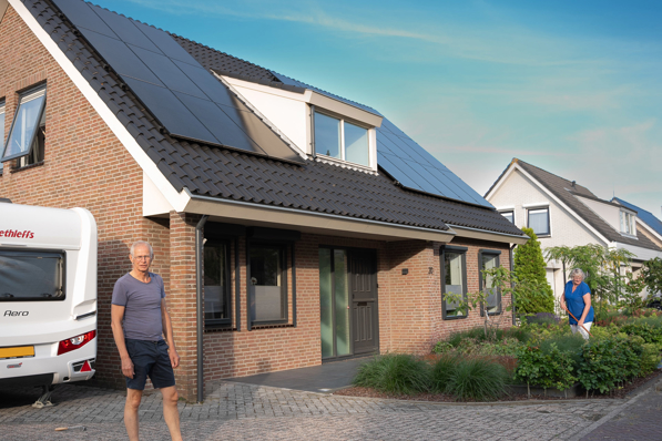 Man voor zijn huis met op het dak PVT-panelen van HR Energy, onderdeel van een duurzaam PVT-systeem met warmtepomp.