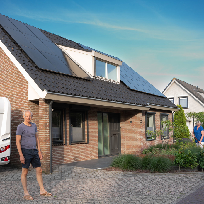 Man voor zijn huis met op het dak PVT-panelen van HR Energy, onderdeel van een duurzaam PVT-systeem met warmtepomp.